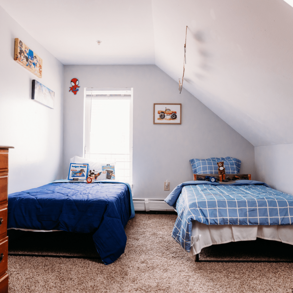 a bedroom with two twin beds, each with blue comforters and colorful children's decor on the walls