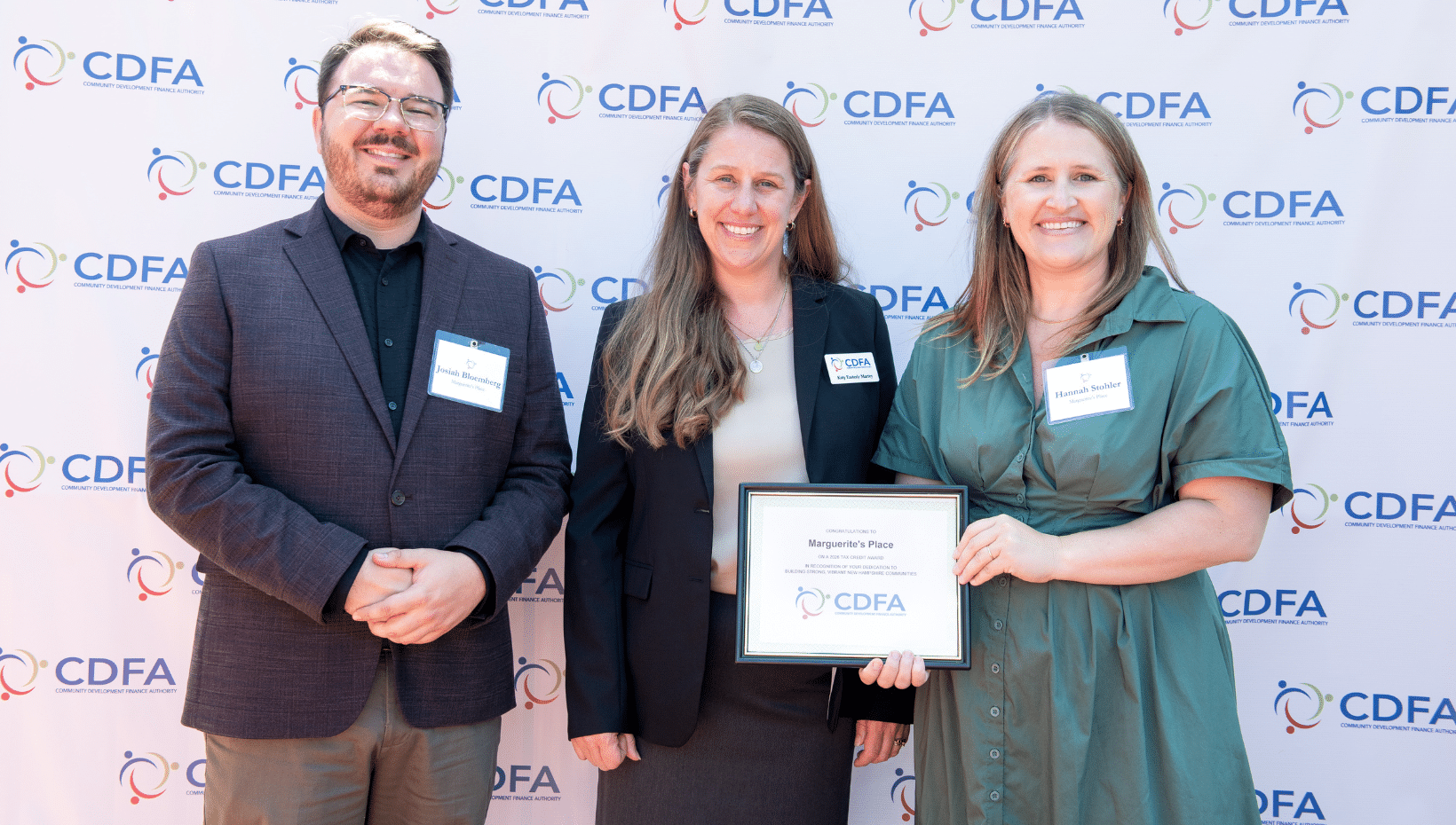 3 well-dressed adults stand holding a plaque in front of the NHCDFA backdrop at the awards ceremony